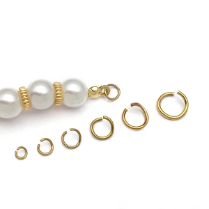 Macro view of assorted golden jump rings for jewelry making with elegant pearl accents