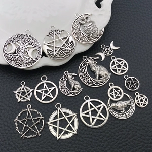 Detalle macro de varios colgantes de plata antigua con luna, búhos y pentagramas