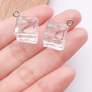 Detailopname van hars ijsblokjes hangers met metalen ringen vastgehouden in de hand