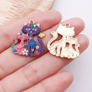 Détail macro de breloques chat en émail coloré avec dos en métal doré et motifs floraux