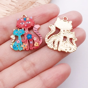Détail de breloques chat colorées avec motifs floraux et dos doré à texture fine