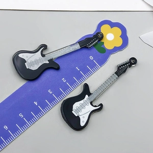 Detailansicht zweier schwarzer Gitarrenanhänger auf einem Lineal zur Größenmessung