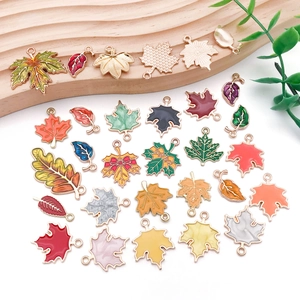 Detailed flat lay of colorful enamel leaf charms with gold trim for DIY jewelry making