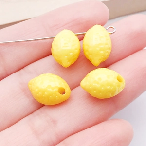 Dettaglio di una mini perla di limone in acrilico per gioielli fai-da-te nella mano