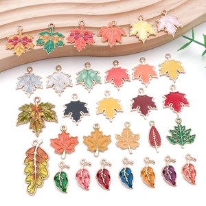 Macro view of colorful enamel maple leaf pendants with golden metal frames for DIY jewelry
