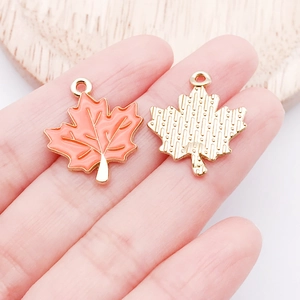 Detail of maple leaf pendant with orange enamel finish and textured gold metal back