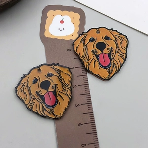 Detailed view of two Golden Retriever acrylic charms next to a ruler for scale