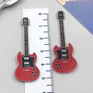 Detail showing two red acrylic electric guitar charms measured with a ruler for scale