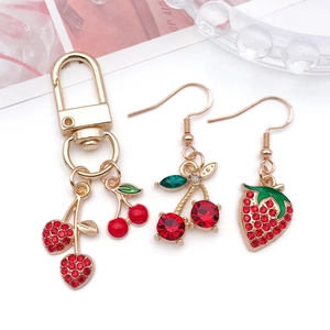 Detail of red rhinestone cherry and strawberry fruit charms on golden metal keychains