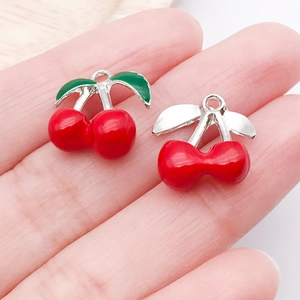 Macro detail of cherry-shaped alloy pendants on hand for DIY jewelry making