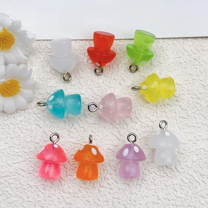 Vista plana de dijes de setas de resina luminosa de colores con anillos para joyería de DIY