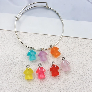Detalle de dijes de setas de resina de colores en una pulsera de alambre metálico ajustable