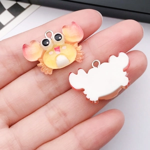 Macro view of cute orange resin crab pendant for DIY jewelry with metal loop detail