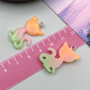 Detailed macro view of two glittery gradient resin cat charms for DIY jewelry making