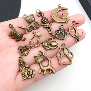 Vintage bronzen kattenhangers en pootjes bedeltjes getoond in de hand voor maat