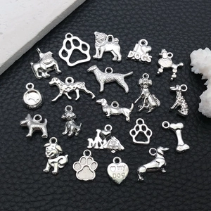 Macro shot of 21 silver dog-themed metal pendants and paw charms on black leather