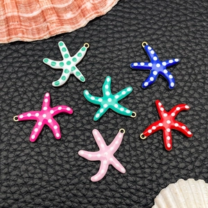 Macro shot of colorful enamel starfish charms with gold edges and polka dots for DIY jewelry
