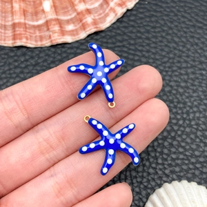 Macro shot of blue starfish charms with white dots and gold plating for jewelry making