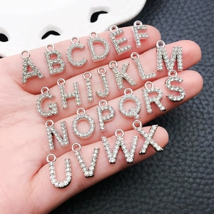 Close-up of sparkling rhinestone-encrusted silver alphabet pendants held in hand
