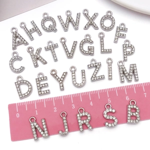 Macro shot of rhinestone-inlayed letter charms A-Z with a ruler showing 1.5cm size