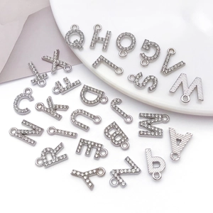 Macro shot of silver-colored rhinestone alphabet pendants with metal texture for DIY jewelry