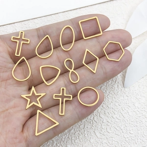 Ciondoli geometrici in acciaio dorato in mano per la creazione di gioielli fai-da-te