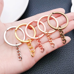 Detail of five colored metal keychains with tail chains held by hand on leather background
