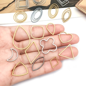 Mano che tiene vari telai geometrici dorati, argentei e grigi per gioielli fai da te