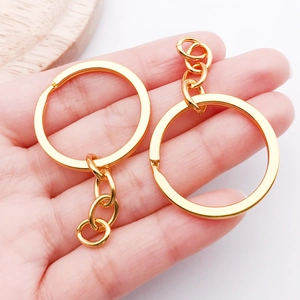 Close-up of dual gold-plated metal keychains with chain links held to show size