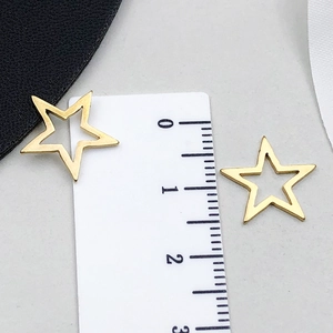 Dettaglio di un ciondolo a stella dorata da 1,5 cm con design traforato su sfondo grigio