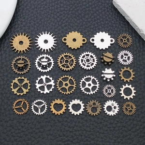 Assorted steampunk metal gear charms in bronze and silver on black leather surface