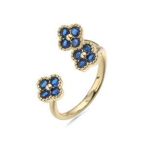Detail van verstelbare gouden ring met blauwe klaverblaadjes en glanzende kristallen