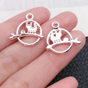 Detail von silbernen Katzenanhängern für DIY-Schmuck auf dunklem Lederhintergrund