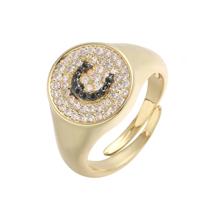 Detalle de anillo de sello dorado con pavé de circonitas y letra C en piedras negras