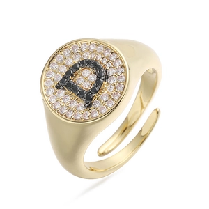Detalle de anillo dorado con letra D y circonitas cúbicas blancas y negras brillantes