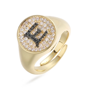 Detalle macro de anillo dorado con letra E incrustada de circonitas negras y claras