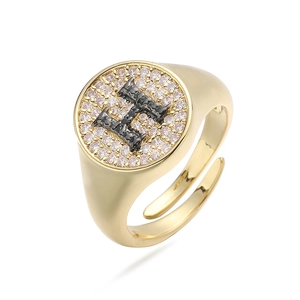 Detalle de anillo ajustable dorado con letra H y circonitas brillantes engastadas