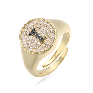 Detalle de anillo dorado con letra I y circonitas cúbicas blancas y negras incrustadas