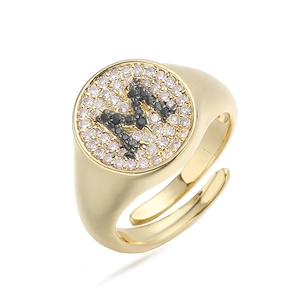 Vista detallada de anillo de oro con pavé de circonitas blancas y negras y letra M