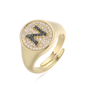 Detalle de anillo ajustable dorado con circonitas blancas y letra N en circonita negra