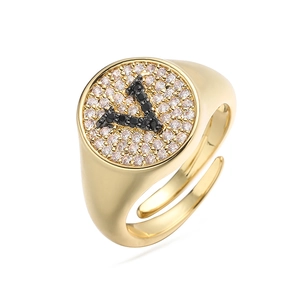 Primer plano de anillo de sello dorado con circonitas blancas y letra V de cristal negro