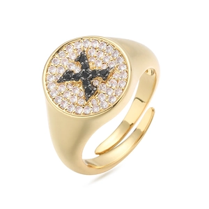 Detalle macro de un anillo de sello dorado con superficie de circonitas y cruz de piedras negras