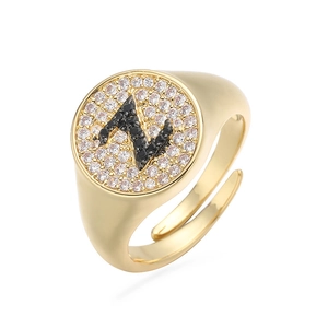 Detalle de anillo dorado con letra N en piedras negras y circonitas blancas