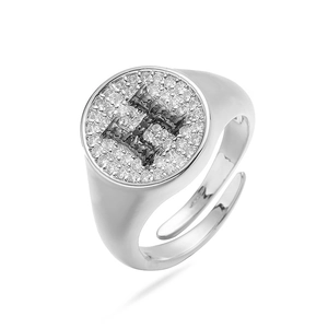 Detalle de un anillo de cobre plateado con pavé de circonitas y letra H en esmalte negro
