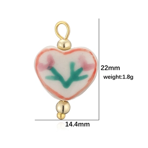 Pendentif cœur en céramique fait main avec motif floral et perles dorées sur fond blanc