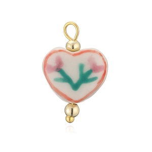 Détail d'un pendentif en céramique en forme de cœur avec motif floral peint à la main et perles