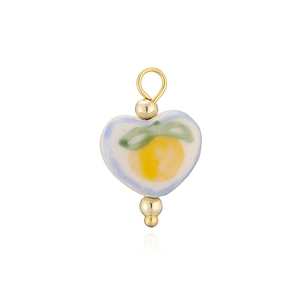 Gros plan d'un pendentif en céramique en forme de cœur avec des fruits jaunes peints