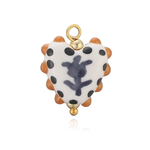 Détail d'un pendentif cœur en céramique avec pois, fleur violette et bordure dorée