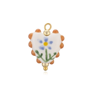 Détail d'un pendentif coeur en céramique avec motif floral bleu et anneau doré