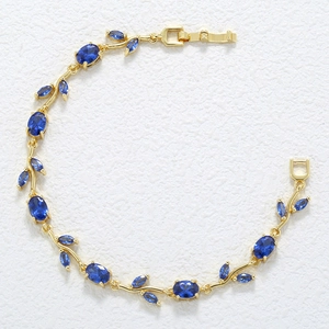 Detailed macro view of the golden vine leaf bracelet with deep blue marquise-cut stones